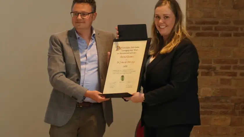 Foto van Astrid Eeuwes die de Dr. J. van der Biltprijs uitgereikt krijgt.