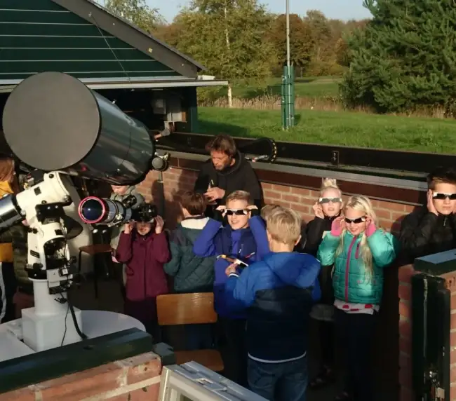 Foto van leerlingen bij een telescoop.